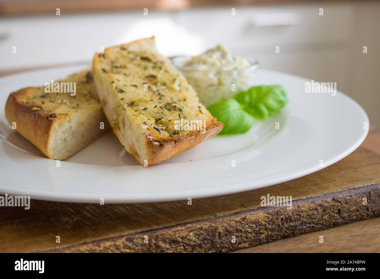 Essen Fotografie von Knoblauch Knoblauch Brot und Butter auf einem weißen Porzellanteller Stockfoto