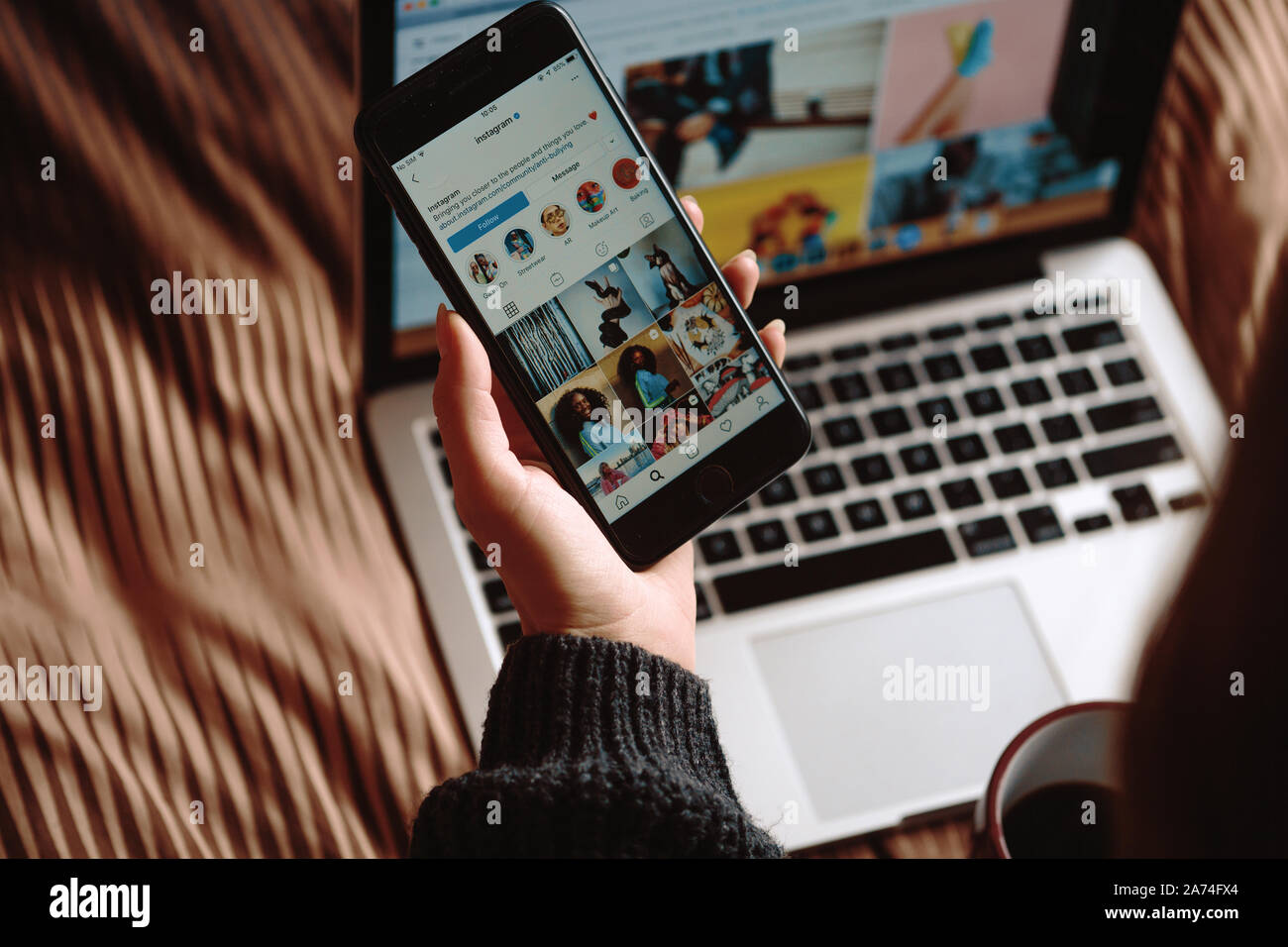Plzen, Tschechische Republik/28. Oktober 2019: Schöne junge Mädchen auf dem Bett zu sitzen mit Laptop mit Tasse Kaffee und beobachten Instagram auf dem Bildschirm Stockfoto