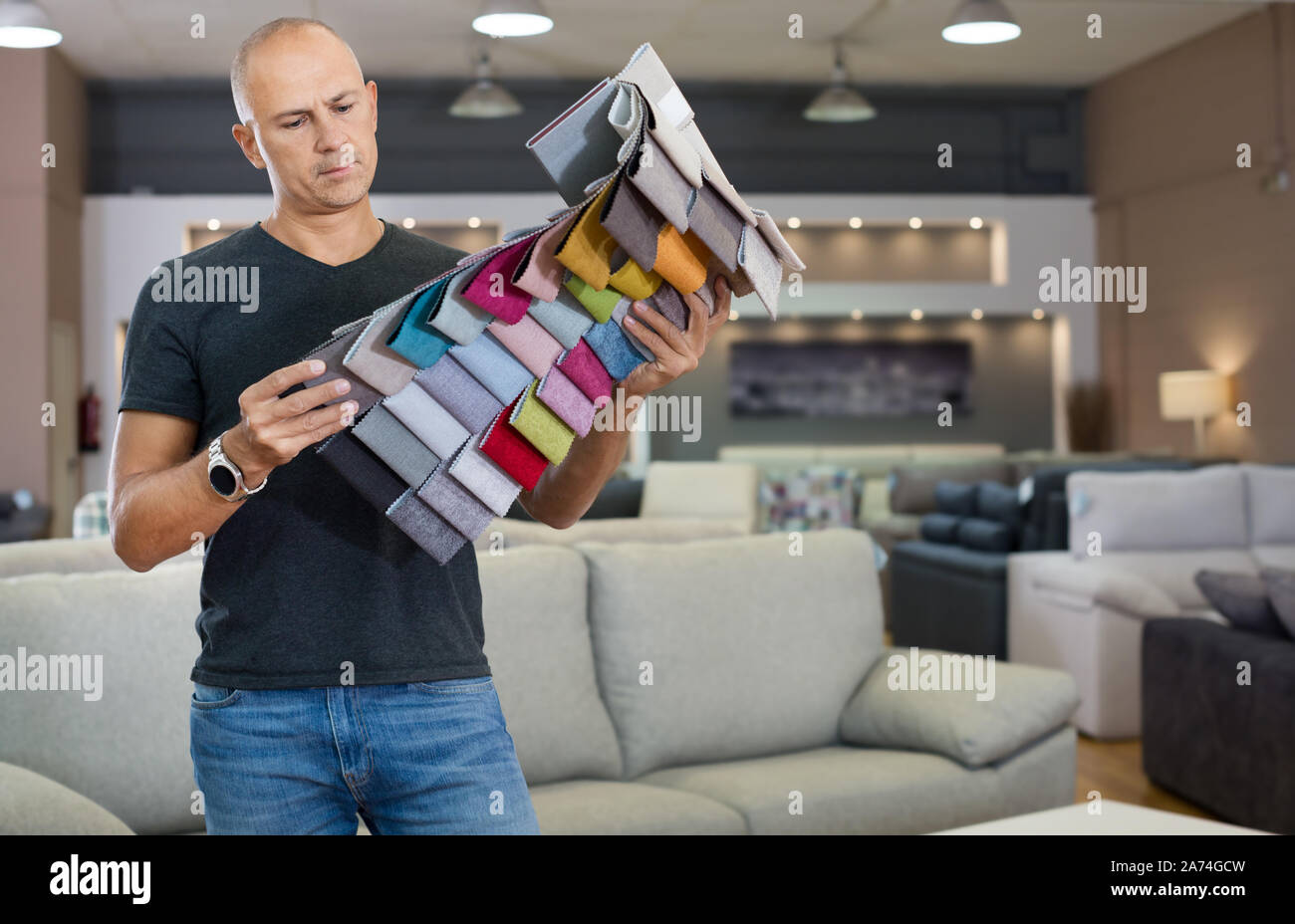 Männliche Kunden Auswahl Bezugsstoff aus Katalog mit Proben im Möbel shop Stockfoto