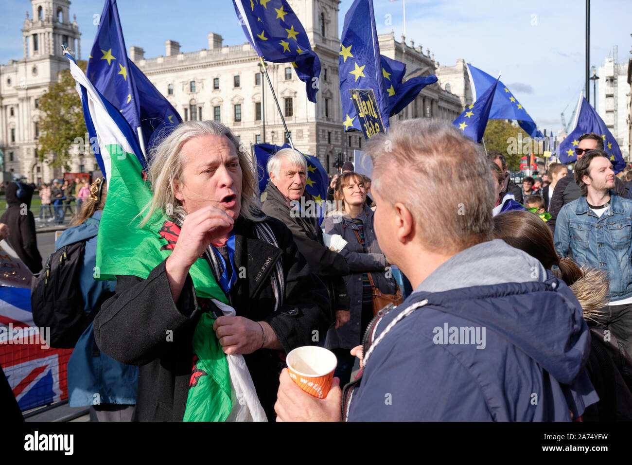 Westminster, England, UK. 30. Oktober 2019. Bleiben die Demonstranten vor dem House of Commons feiert eine weitere Verzögerung bei der Umsetzung Brexit hervorhebt, dass die gesetzte Frist von Halloween wird gehen mit der UK noch in der Europäischen Union, im Gegensatz zu den Versprechen der Premierminister. Demonstrant mit Flagge von Wales in Diskussion mit Anhänger Kredit verlassen: JF Pelletier/Alamy Leben Nachrichten. Stockfoto