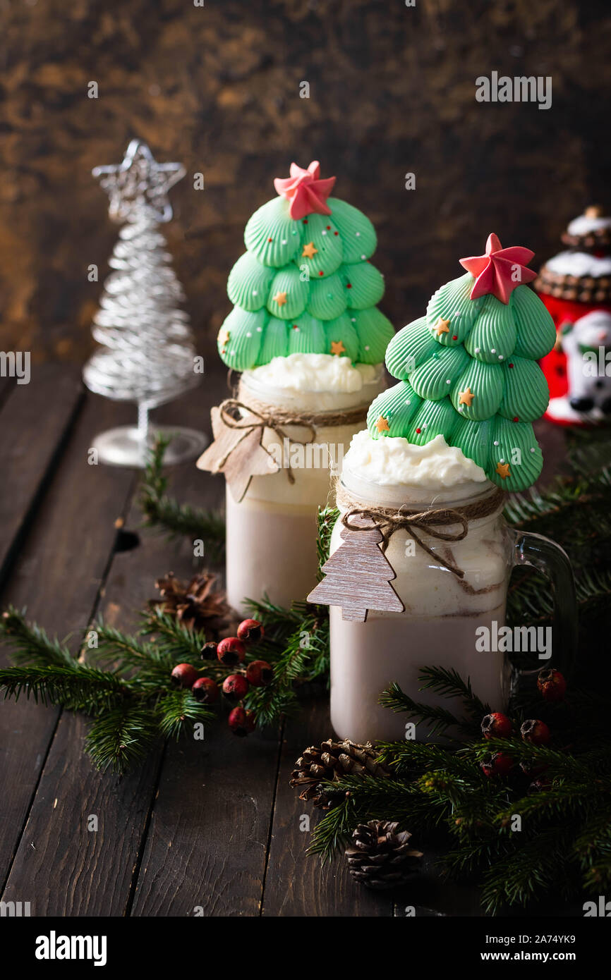 Festliche Silvester und Weihnachten Kakao in großen Gläsern mit Schlagsahne mit einem Baiser Weihnachtsbaum dekoriert. Winter Drink auf einem dunklen backgroun Stockfoto