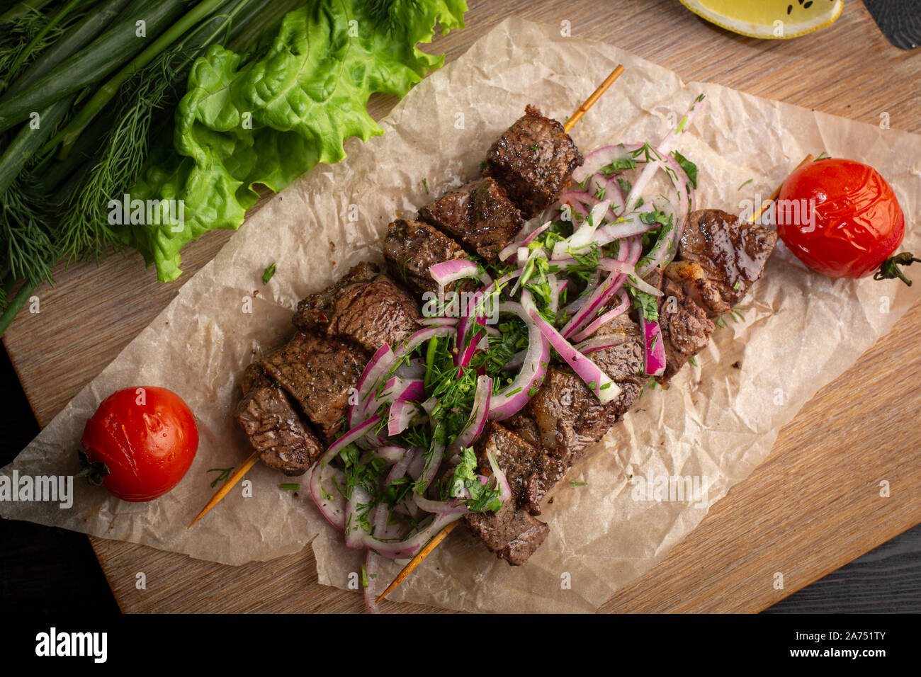 Rindfleisch Kebab mit eingelegten Zwiebeln und Koriander auf einem Holzbrett mit Blattgrün auf einem dunklen Hintergrund eingerichtet Stockfoto