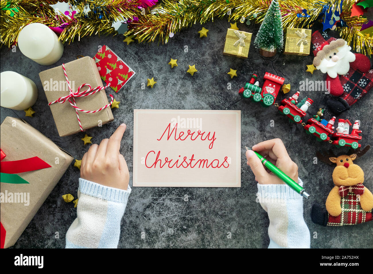 Hand schreiben Frohe Weihnachten auf Grußkarte während der Weihnachtszeit und Geschenk Festival, Dekorationen mit Christmas Ornament auf Tisch Stockfoto