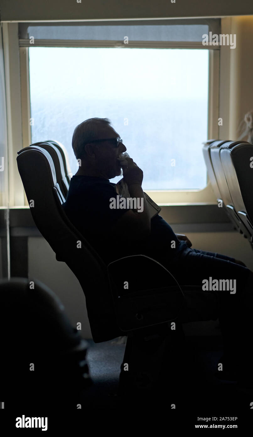 Ein Mann essen auf einem Blue Star Fähre. Stockfoto