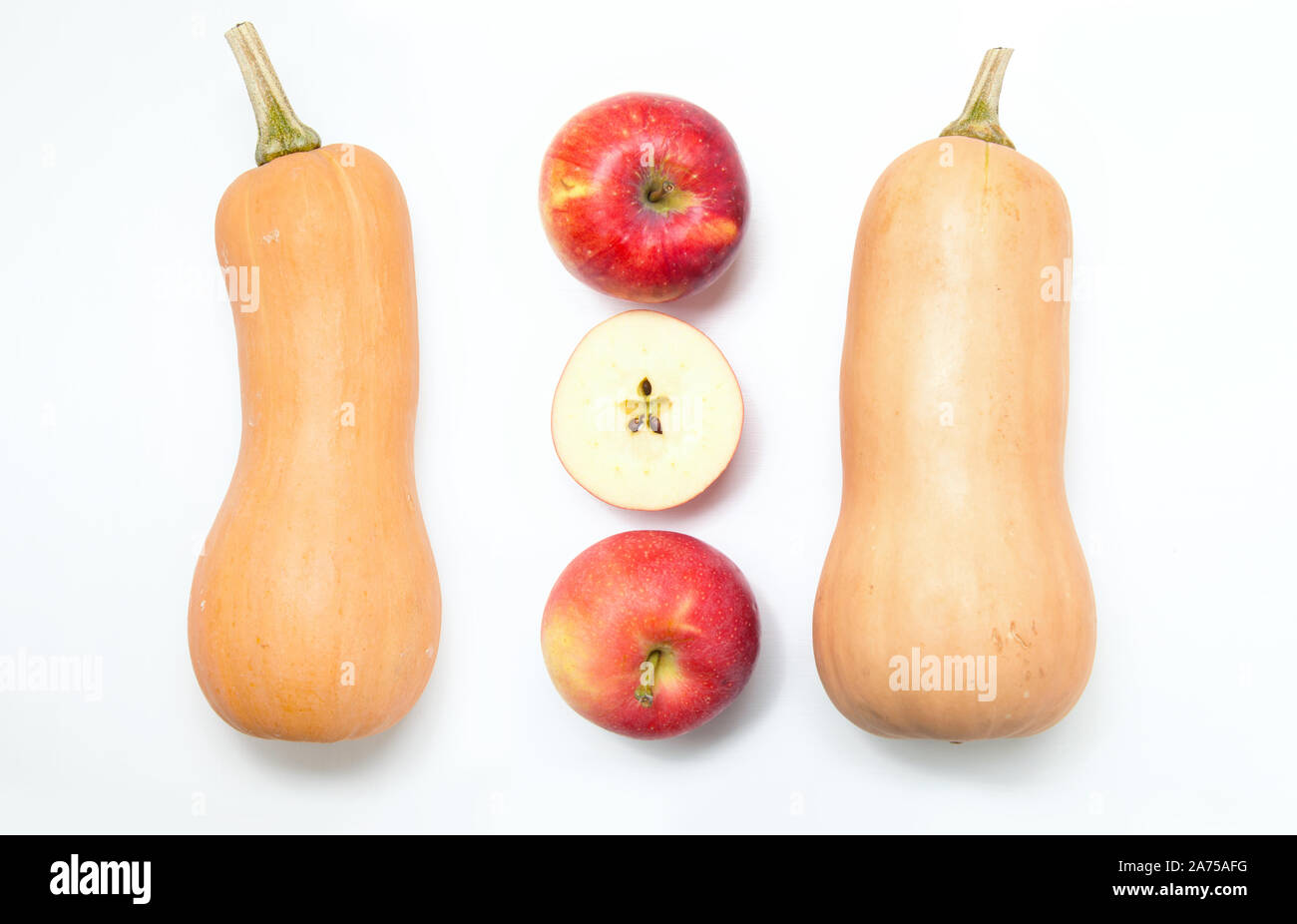 Zwei Kürbisse und 3 ganze Äpfel und Scheiben auf einem weißen Hintergrund. Zutaten für Ernährung Salat oder frisch gepressten Saft. Stockfoto