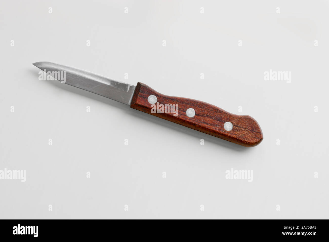 Küchengeräte - ein kleines Messer mit einem hölzernen für Gemüse auf einem hellen Hintergrund. Cooking-Werkzeuge. Stockfoto