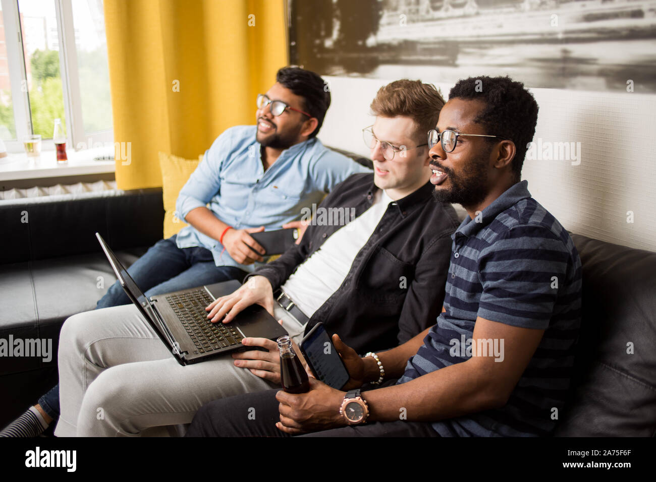 Gruppe von Multiethnischen männliche Freunde gerade online Sport Spiel mit Laptop auf dem Sofa zu Hause sitzen, Warten auf Sieg nach Wetten in Online bookmak Stockfoto