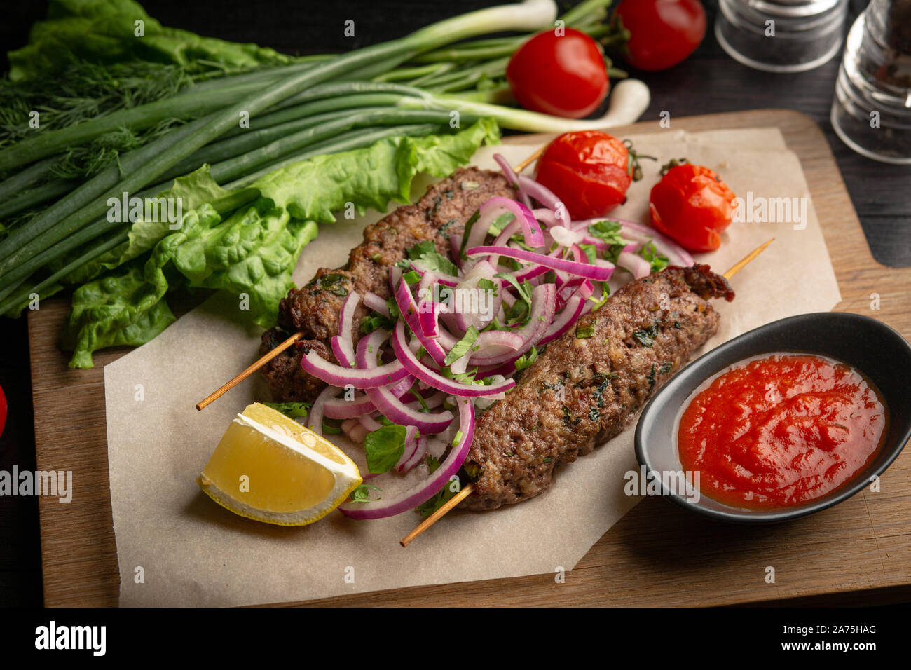 Lula Kebab von Rindfleisch am Spieß mit Zwiebeln, grünen, Ketchup und Zitrone auf ein Brett auf einem dunklen Hintergrund Stockfoto