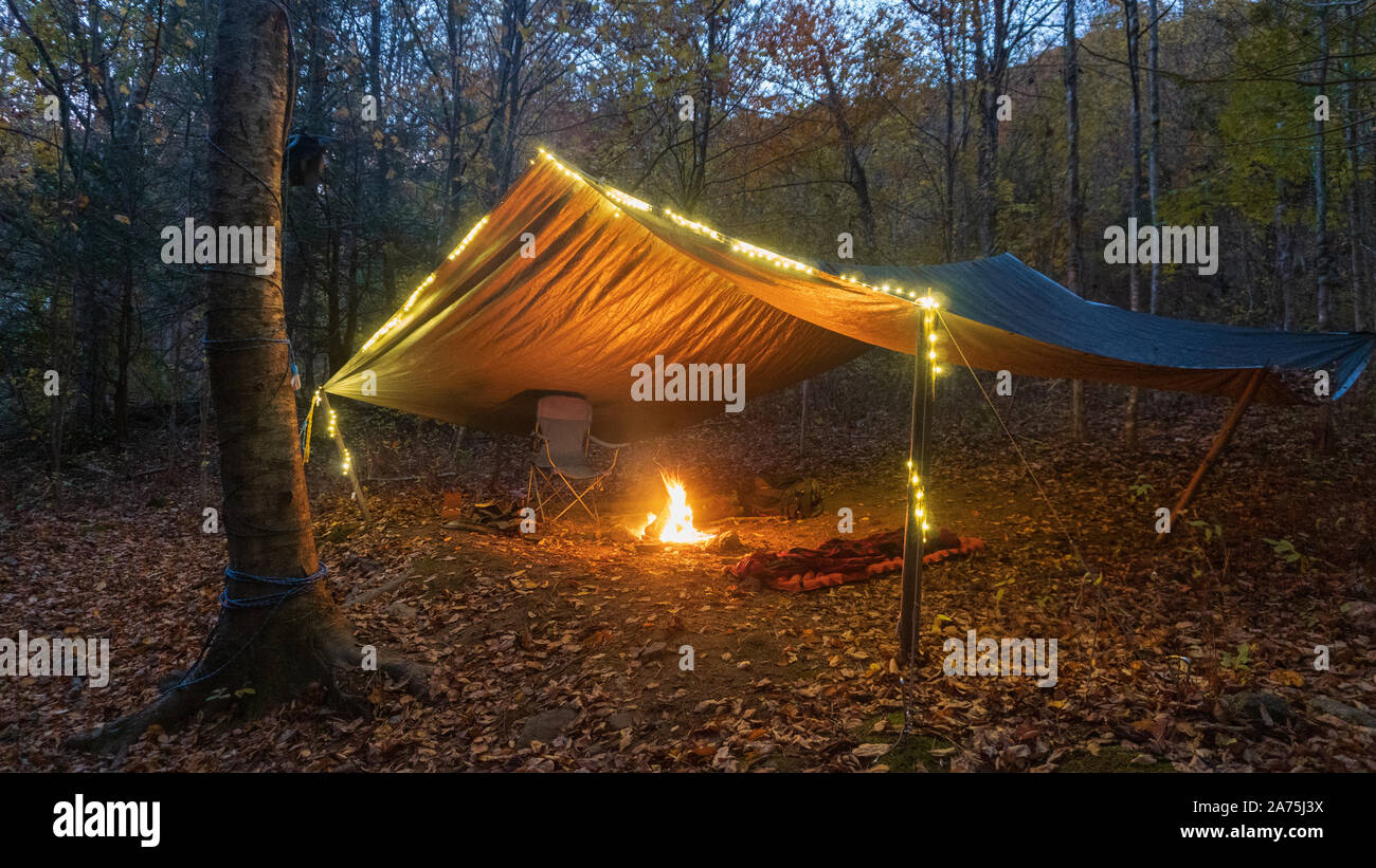 Primitive Tarp Tierheim mit Lagerfeuer und Lichterketten. Survival Bushcraft Setup in den Blue Ridge Mountains in der Nähe von Asheville. Stockfoto
