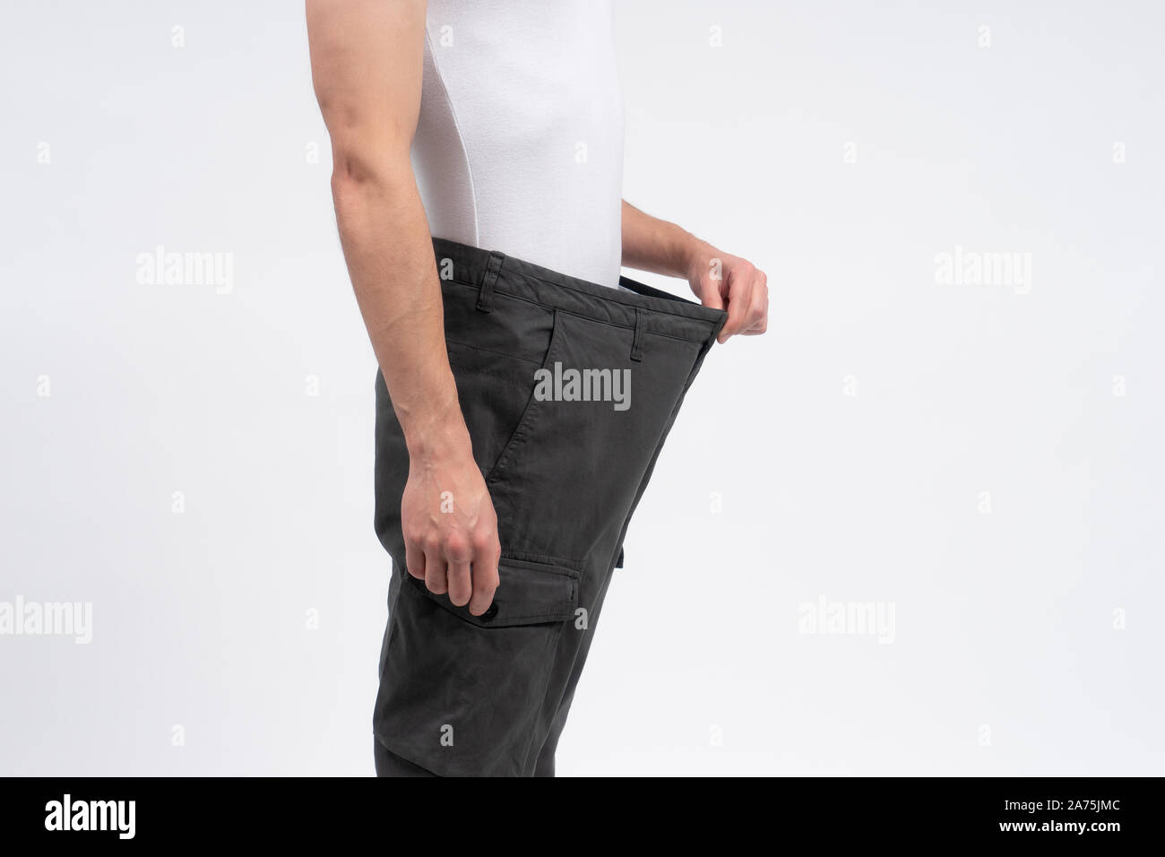 Dünner Mann seine Hose stretching Verlust von Gewicht nach der Diät zu zeigen. Person isoliert auf weißem Hintergrund mit kopieren. Andere Größe kleider Lieferung. Stockfoto