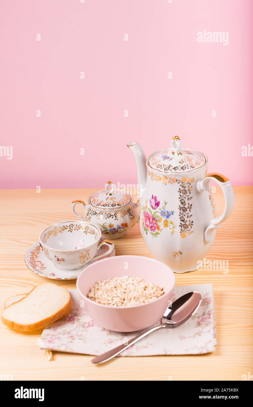 Haferflocken in einem rosa Platte und schöne Vintage Tee Utensilien Stockfoto