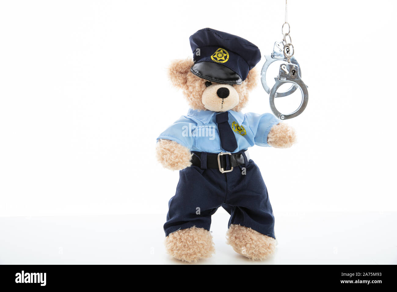 Polizei und Verhaftung Konzept. Niedlichen Teddybären in Polizeioffizier einheitliche und Handschellen vor weißem Hintergrund Stockfoto