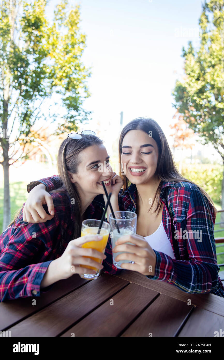 Zwei junge Frauen trinken Saft und Limonade in den Park an einem sonnigen Tag Stockfoto