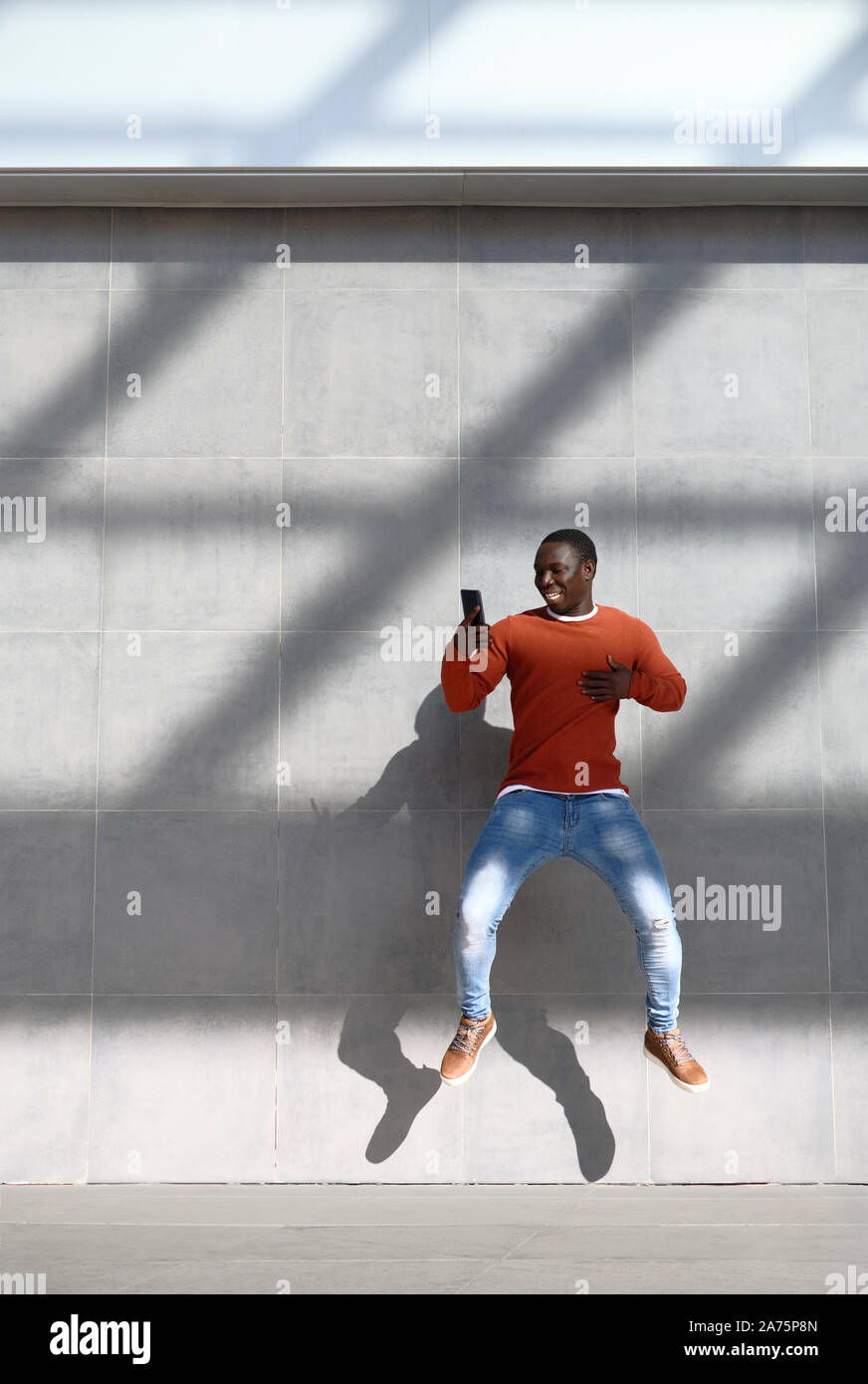 Afrikanischer Mann vor Freude hüpfend Holding Tel. Stockfoto