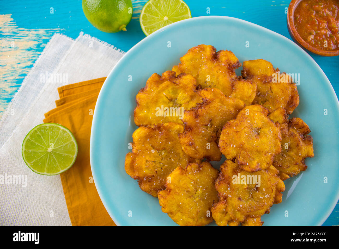 Essen Fotografie eines blauen Platte mit frittierten Kochbananen tostones Lateinamerikas oder patacones mit Limetten. Stockfoto