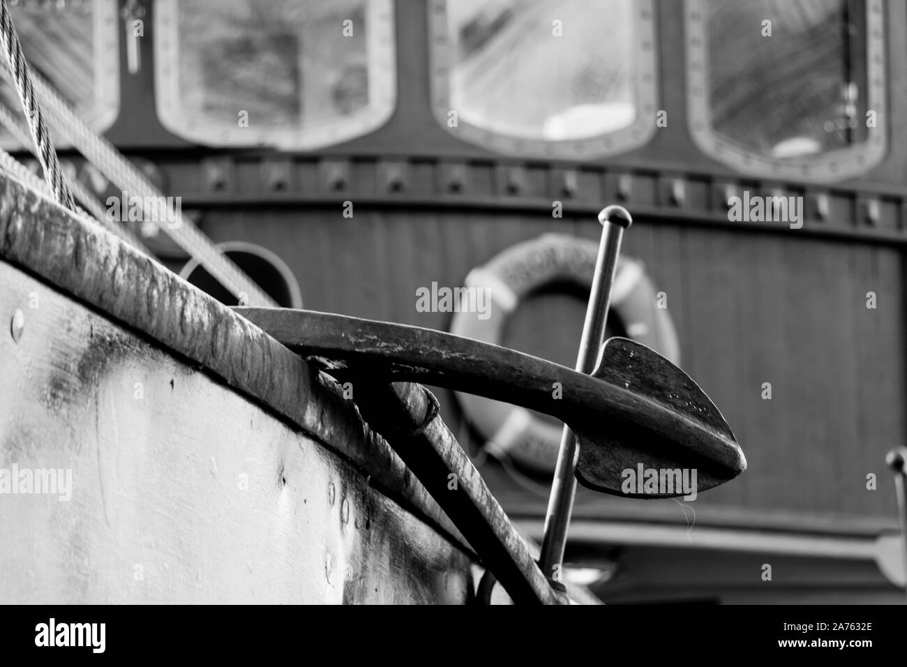 Schwarz und Weiß in der Nähe Blick auf ein altes Fischerboot Anker mit Boot Windows und Rettungsring im Hintergrund Stockfoto