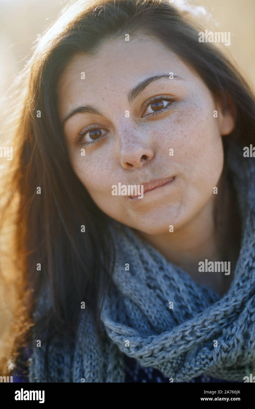 Junge erwachsene Frau im Freien lächelnd und mit Blick auf die Kamera Stockfoto