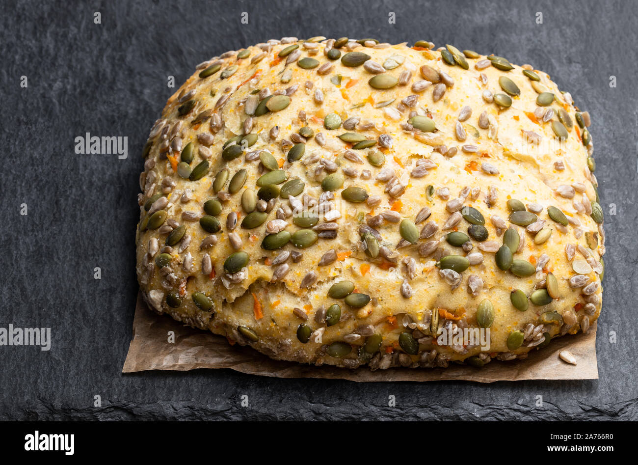 Saatgut fallenden Karotte Brot bloomer Laib auf schwarzen Stein Hintergrund Stockfoto