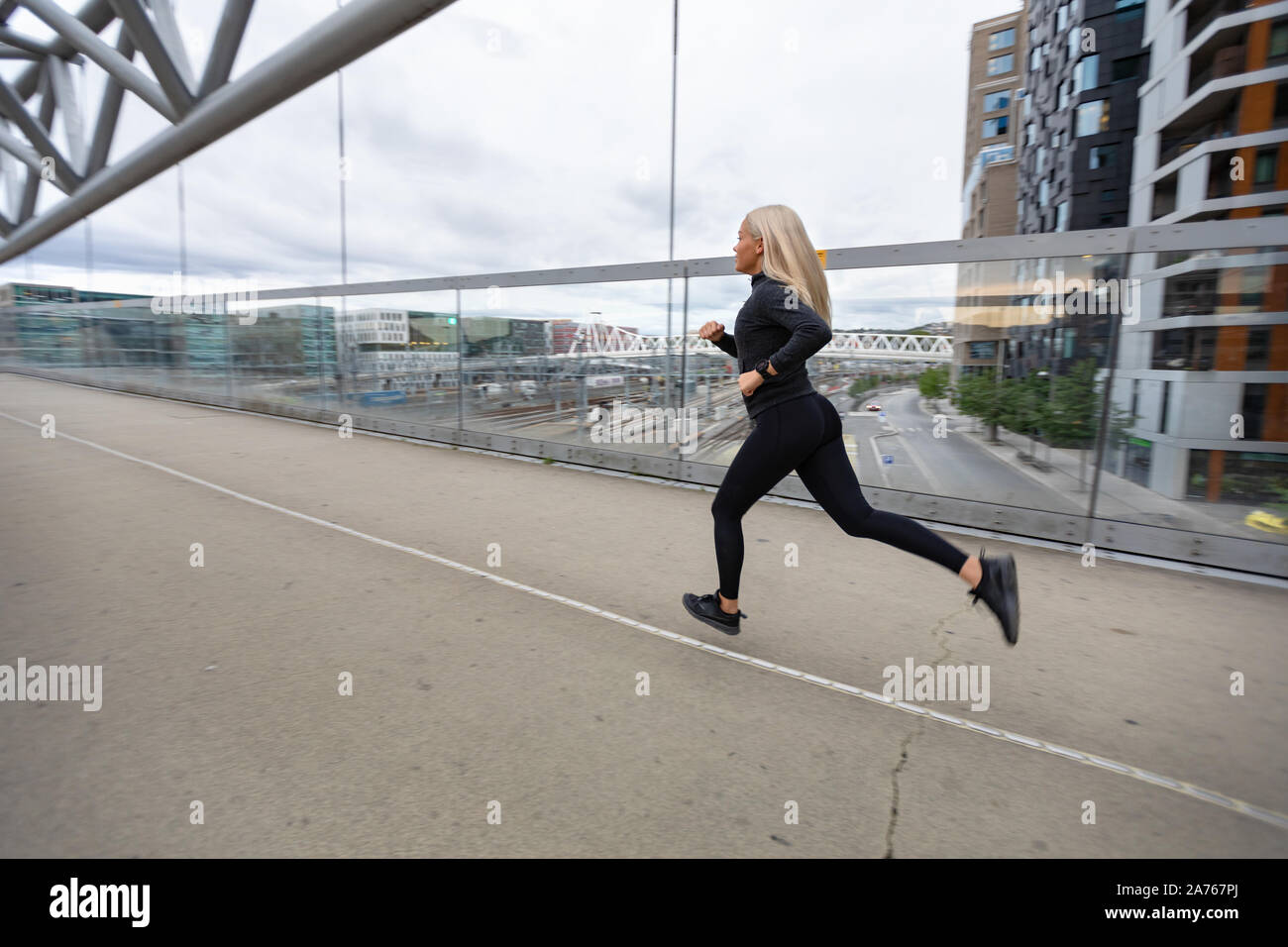 Weibliche Jogger in Schwarz workout Outfit in der modernen Stadt Umgebung Stockfoto