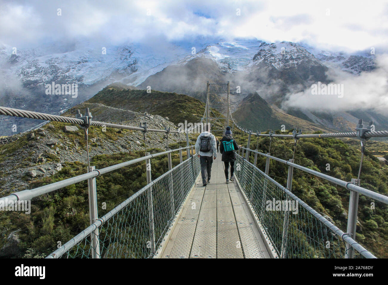 Der Mann und die Frau zu Fuß entlang Hängebrücke von Bergen umgeben ist. Stockfoto