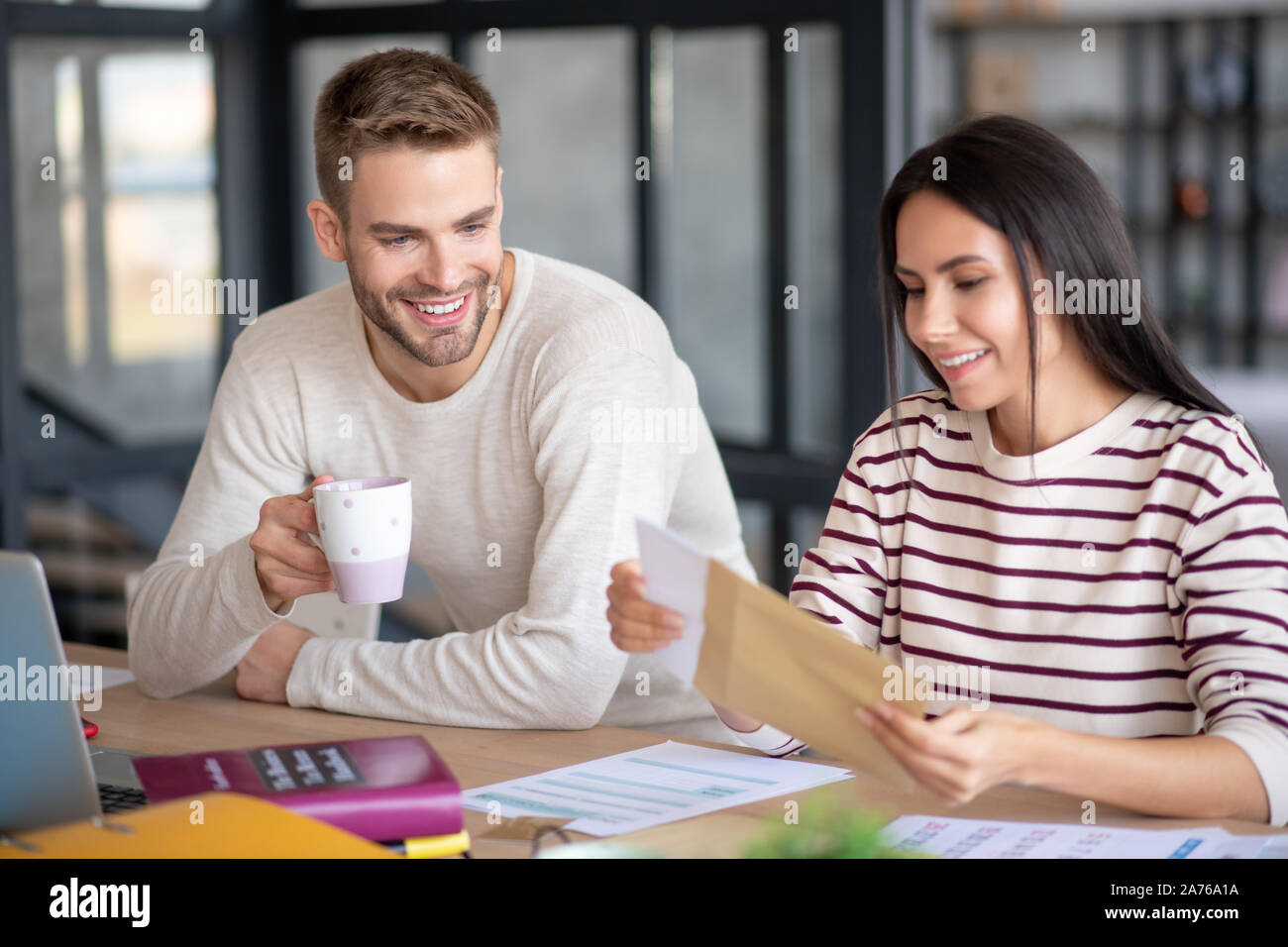 Freundliche Paar lächelnd vor dem Lesen Schreiben von alten Freund Stockfoto