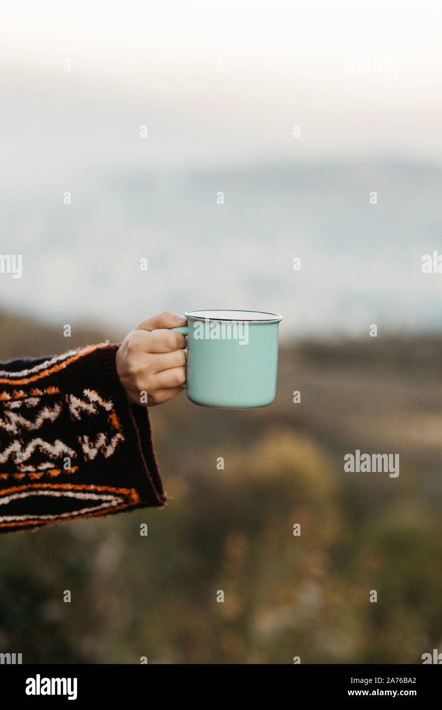 Mockup der weiblichen Hand mit einem Kaffee Keramik pastellgrün Cup in der Natur. Flache Stockfoto