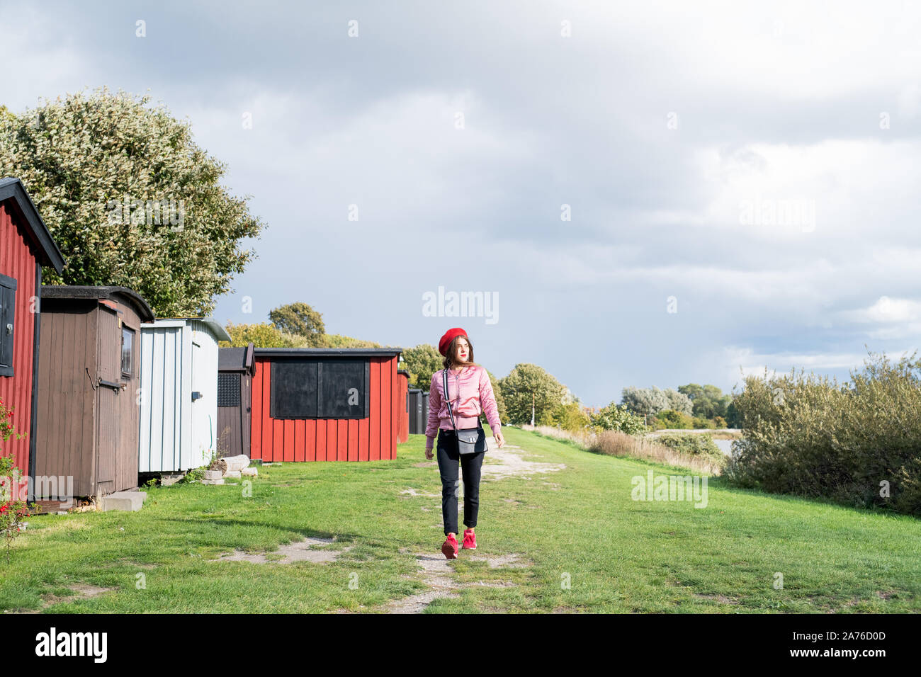 Junge Frau mit Red Hat zu Fuß durch Strandhütten Stockfoto