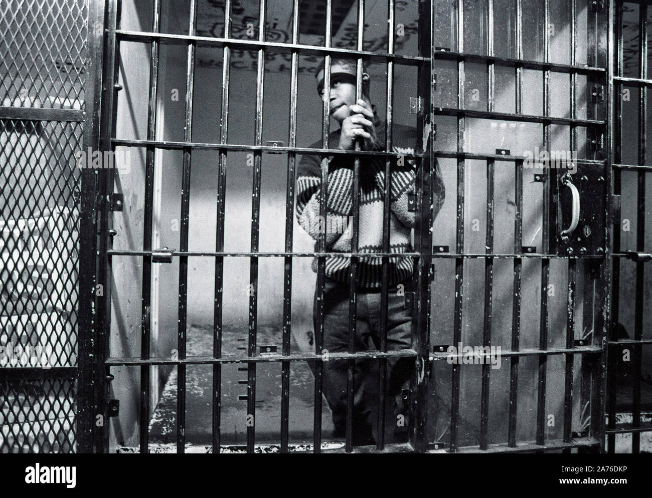 Ein unidentifed afrikanisch-amerikanischer Kriegsgefangenschaft schaut aus einem Betrieb Zelle in Boston Polizei Station B3 in Boston, Ma USA 1987, alle Gefangenen als unschuldig, bis gefunden juilty durch ein Gericht. Foto von Bill belknap. Weitere Infos unter optional Stockfoto