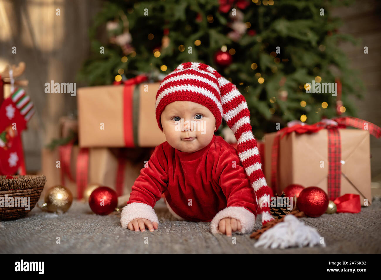 7 Monate altes Mädchen unter den Weihnachtsbaum. Baby Mädchen in Santa  Claus hut mit Geschenke unter dem Weihnachtsbaum Stockfotografie - Alamy