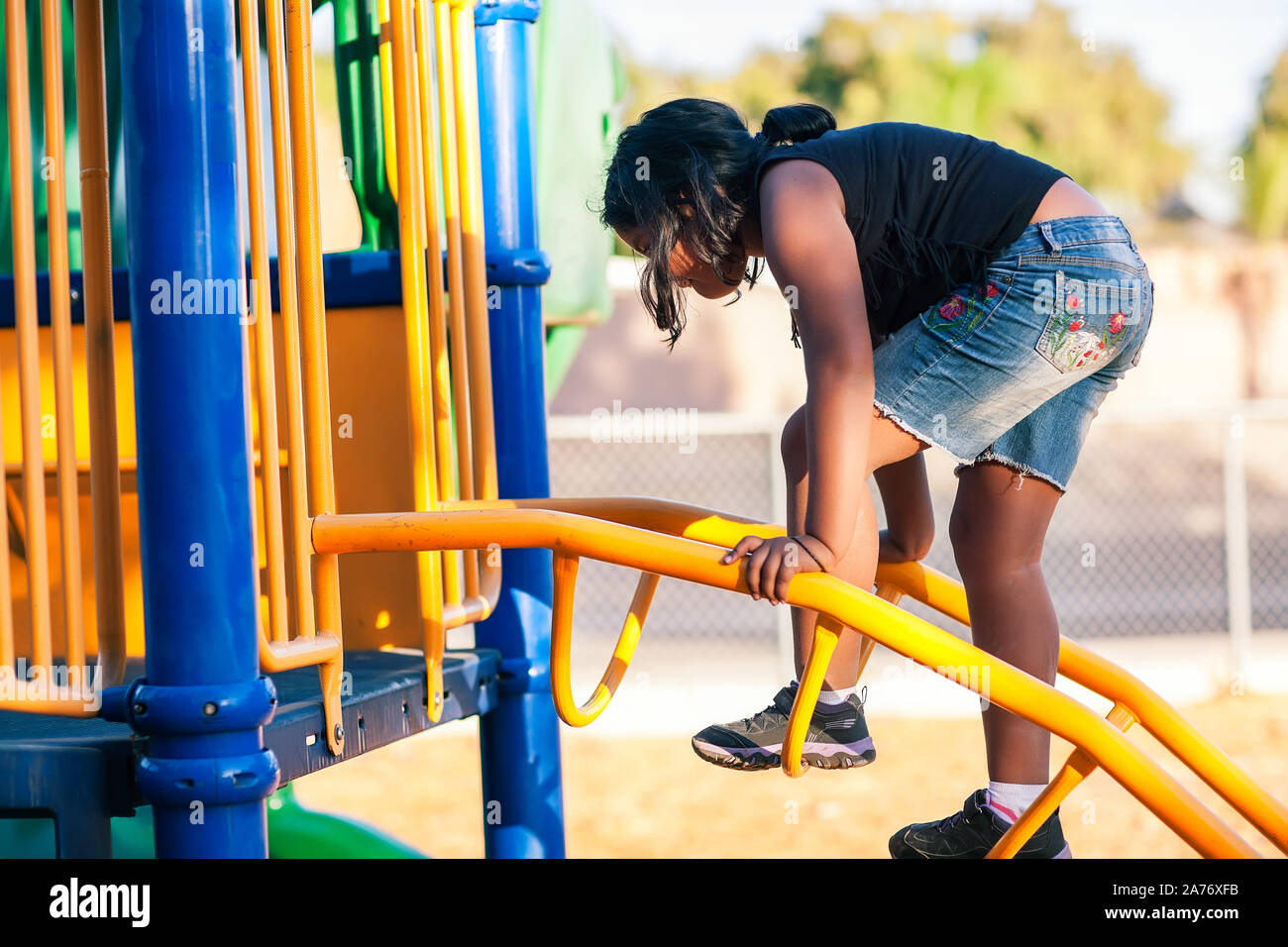 Ein junges Mädchen klettern eine Leiter auf einer Jungle Gym und Ihren Gleichgewichtssinn entwickeln. Stockfoto