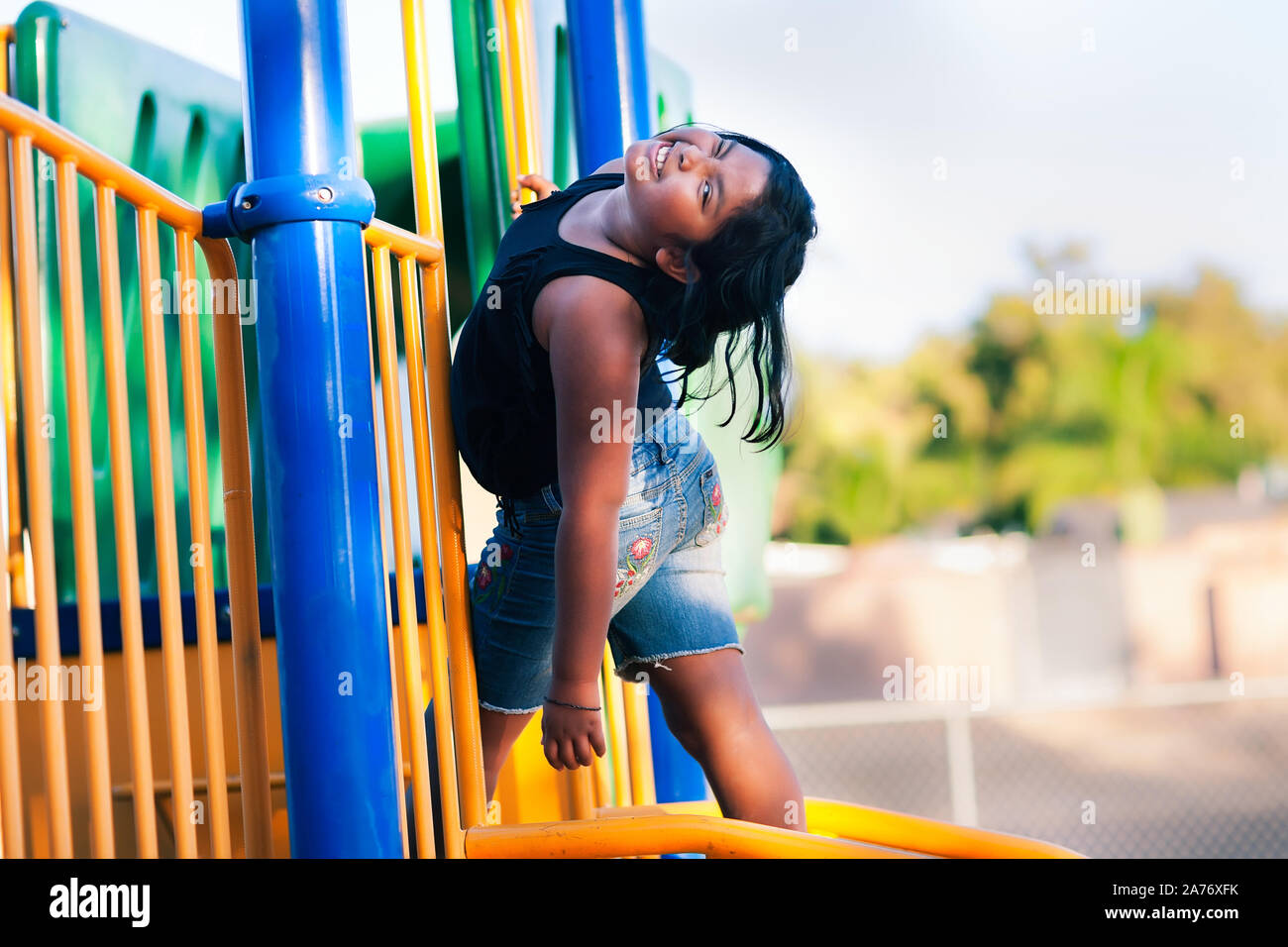 Ein süßes kleines Mädchen Spaß haben, während Sie von einem Kinder Jungle Gym hängt. Stockfoto