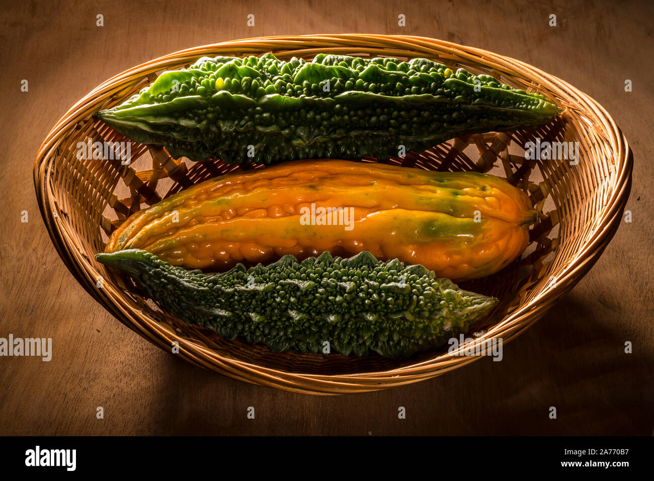 Reif chinesischen bitter Melone in Korb mit indischen bitter Melonen auf Holz Schneidebrett Stockfoto