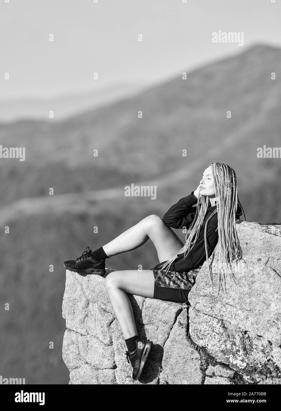 Extreme Konzept. Am Rande der Welt. Frau sitzen am Rand der Klippe in die hohen Berge Landschaft Hintergrund. Wandern ruhigen Moment. Genießen Sie die Aussicht. Touristische Wanderer Mädchen entspannende Kante Cliff. Gefährliche entspannen. Stockfoto