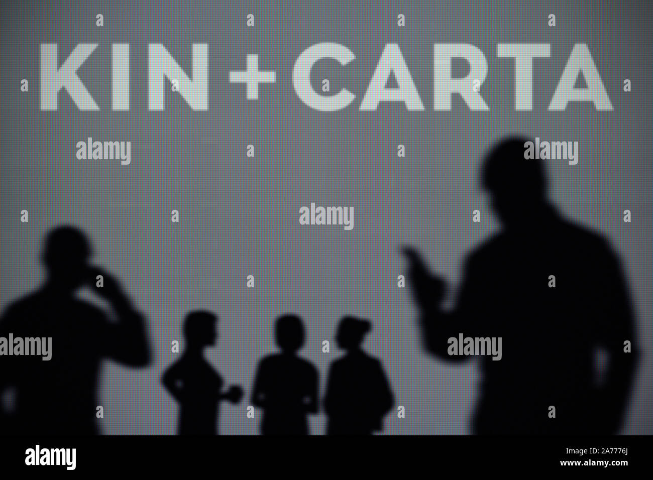 Die Kin- und Carta Logo ist auf einen LED-Bildschirm im Hintergrund, während eine Silhouette Person ein Smartphone verwendet (nur redaktionelle Nutzung) Stockfoto