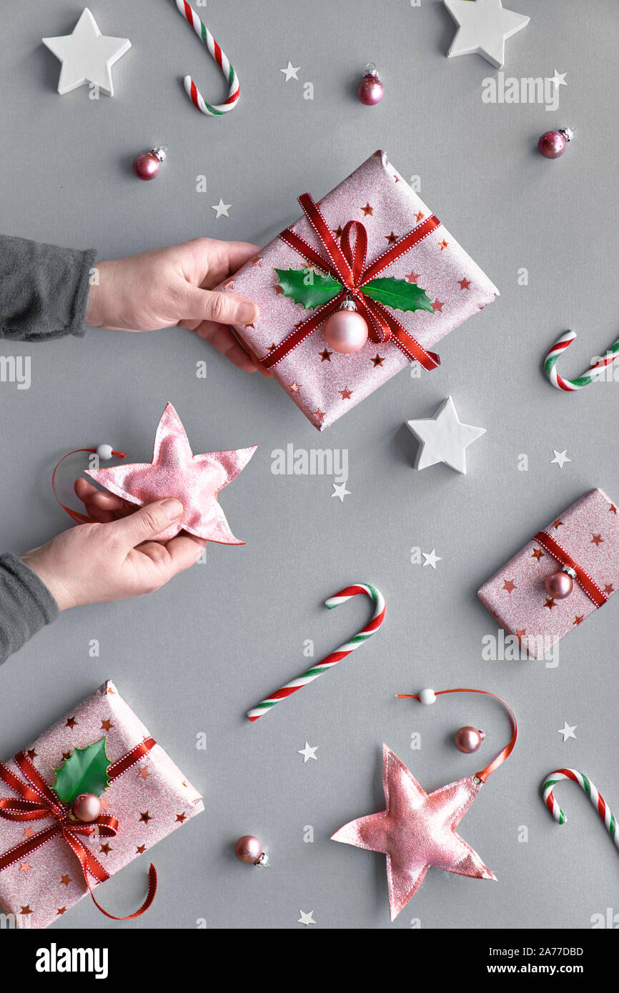 Festliche Weihnachten Hintergrund mit rosa Geschenkboxen, gestreifte Zuckerstangen, Schmuckstücke und Sterne, geometrische Creative flach auf silbernem Papier. Hand, w Stockfoto