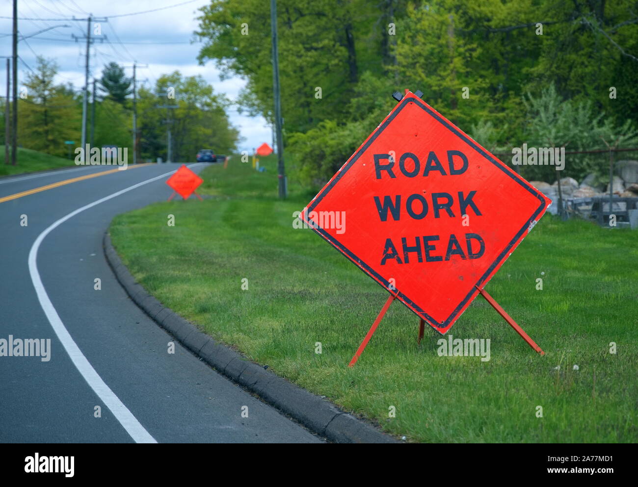 Mehrere orange Road Arbeit vor Zeichen auf der Schulter von der Straße Alarmierung Autofahrer zu verlangsamen. Stockfoto