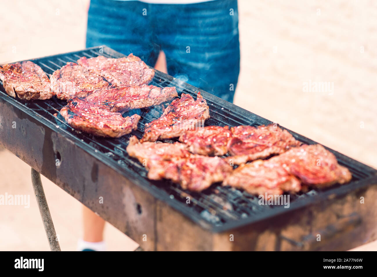 BBQ Beef Steak auf dem Grill rauchen über glühende Kohlen. Mann kochen Grill draußen. Nahaufnahme der leckere Rindersteaks gebraten auf Grill. Organisches Fleisch gebraten auf rustikalen Holzkohle Grill. Stockfoto