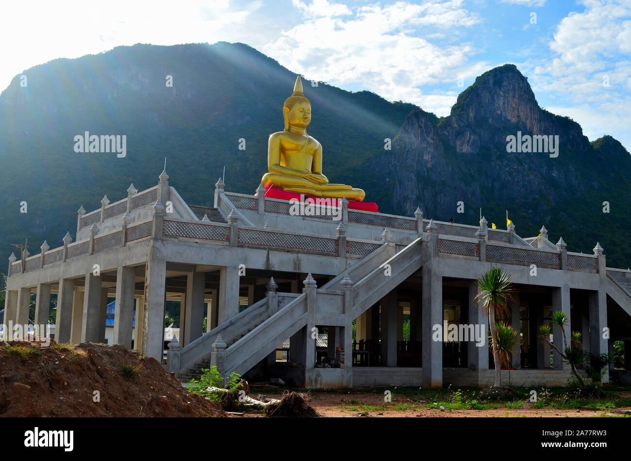 Ein Buddha Bild sitzt auf einem hohen Struktur mit einer Treppe mit Sonnenstrahlen auf Sam Roi Yot Tempel Pranburi Thailand Stockfoto