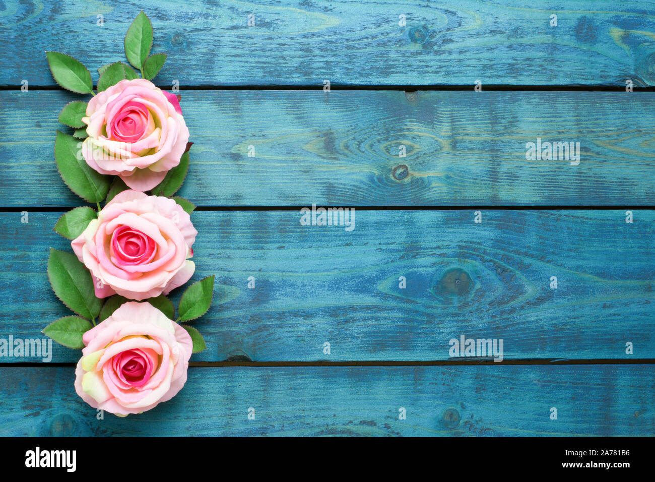 Hochzeit Grenze mit drei rosa Rose Blumen auf blau Holz- Hintergrund Stockfoto