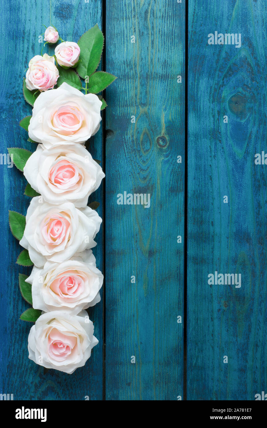 Hochzeit Grenze mit einer Reihe von leichten rosa Rose Blumen auf blau Holz- Hintergrund Stockfoto