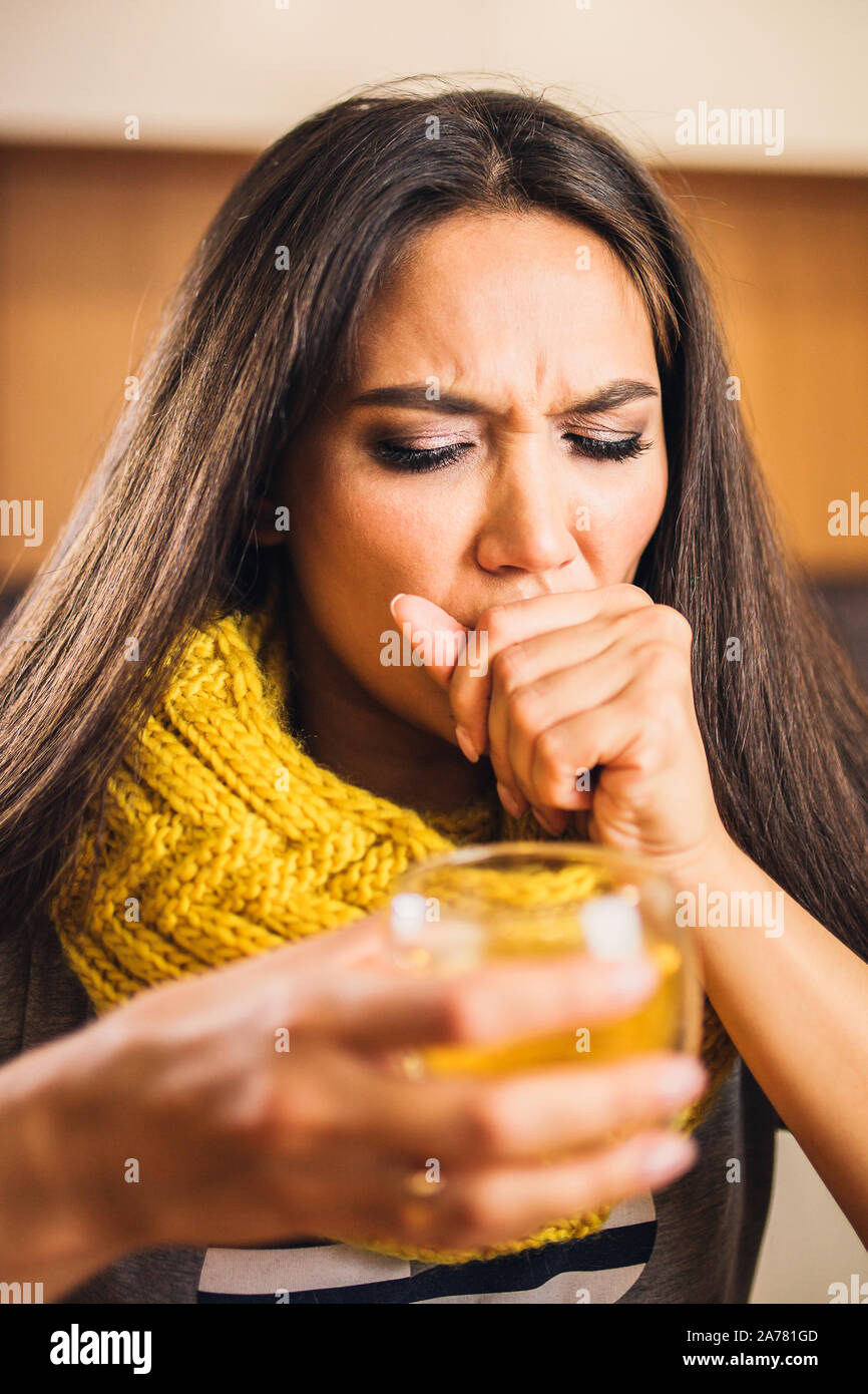 Brunette Mädchen in einen Schal zu Hause mit einer Tasse heißen Tee husten Hard- Behandlung für eine kalte Stockfoto