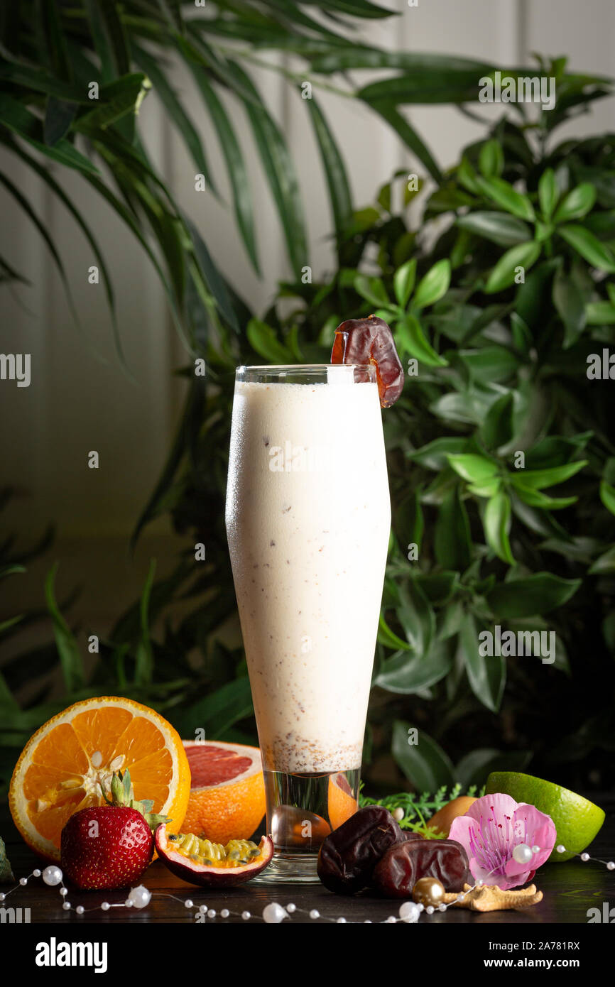 Milchshake mit ein Datum in ein Glas und Früchte auf einem Hintergrund von grünen Blättern Stockfoto
