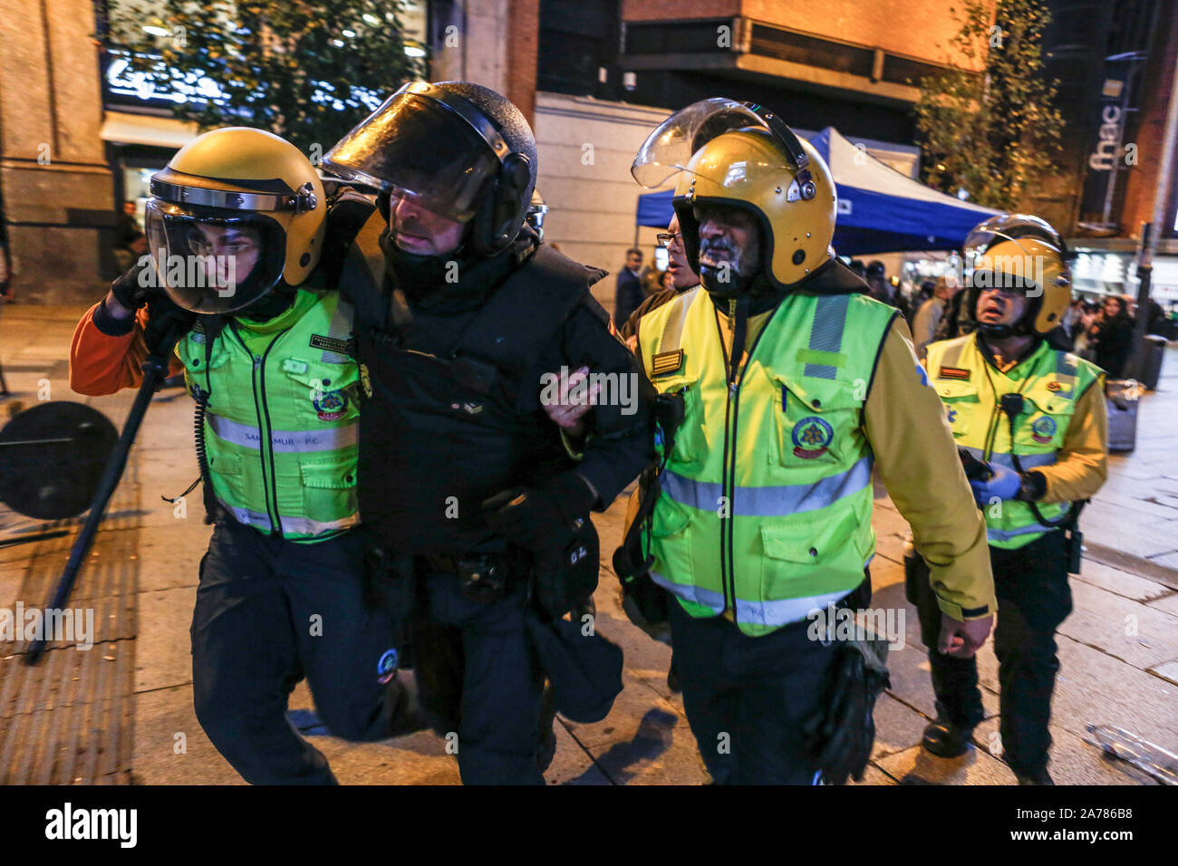 Ein verwundeter Polizist von sanitätern während der Auseinandersetzungen. Hunderte von linken Demonstranten mit der Polizei aneinandergeraten nach einem pazifischen Kundgebung gegen das Oberste Gericht Satz der Katalanischen Politik und Aktivisten. Sie waren mehr als zehn Festnahmen und einige Polizisten wurden verletzt. In einem Versuch der Neuerstellung der gewalttätigen Ausschreitungen von Barcelona die Demonstranten bis Barrikaden in einigen Straßen der Innenstadt angesiedelt. Stockfoto