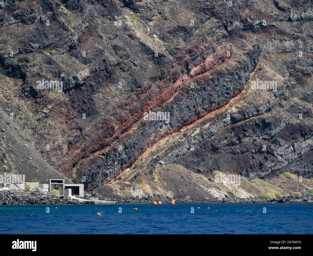 Eine Nahaufnahme vom Meer Wasser eines roten geologischen Schnitt Riss Riss in Santorini lava Cliff Stockfoto