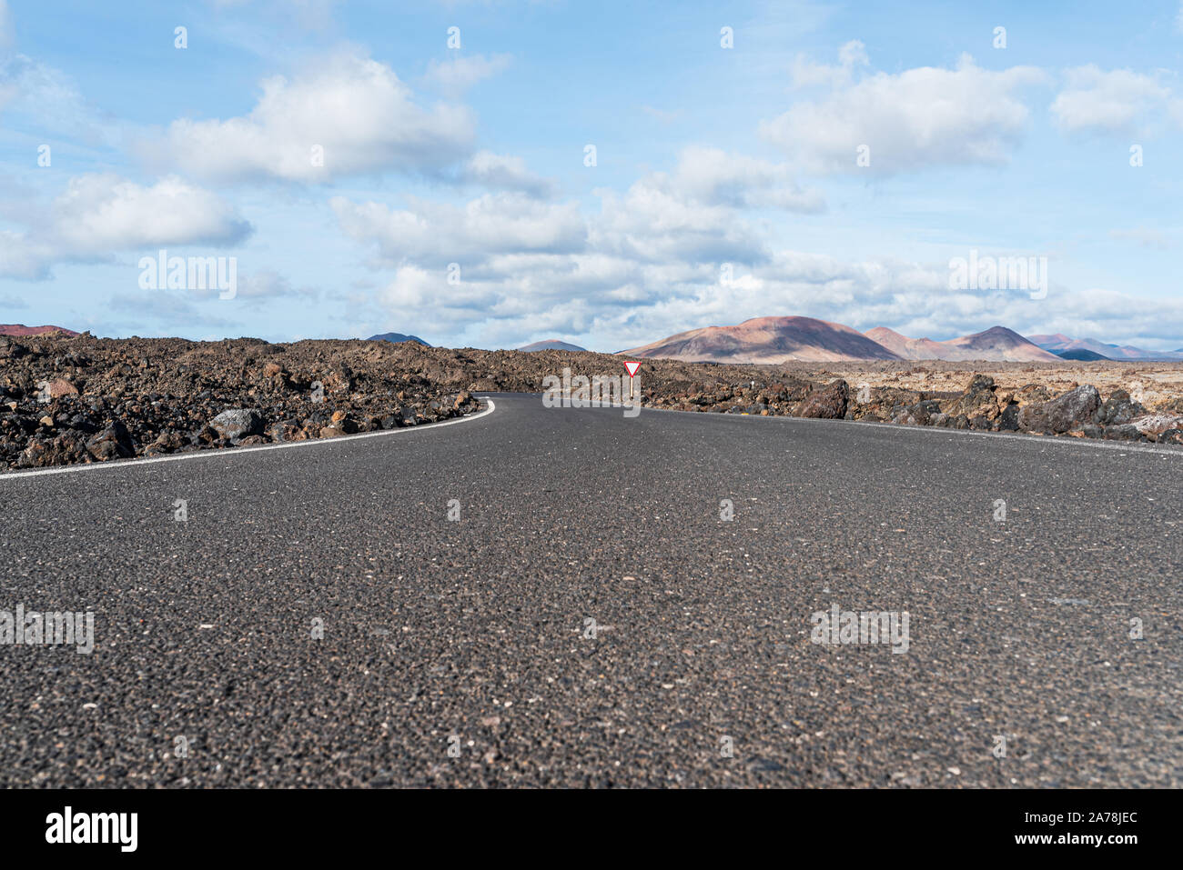 Low Angle View von leeren Asphalt Straße Straße durch Dürren vulkanische Landschaft gegen den blauen Himmel Stockfoto