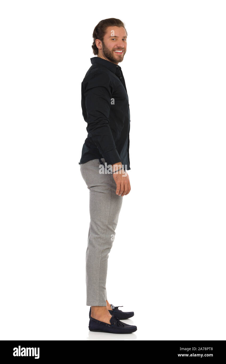 Seitenansicht des Ständigen stattlicher Mann in Mokassins, graue Hose und schwarzes  Hemd. Volle Länge studio Schuß auf weißen isoliert Stockfotografie - Alamy