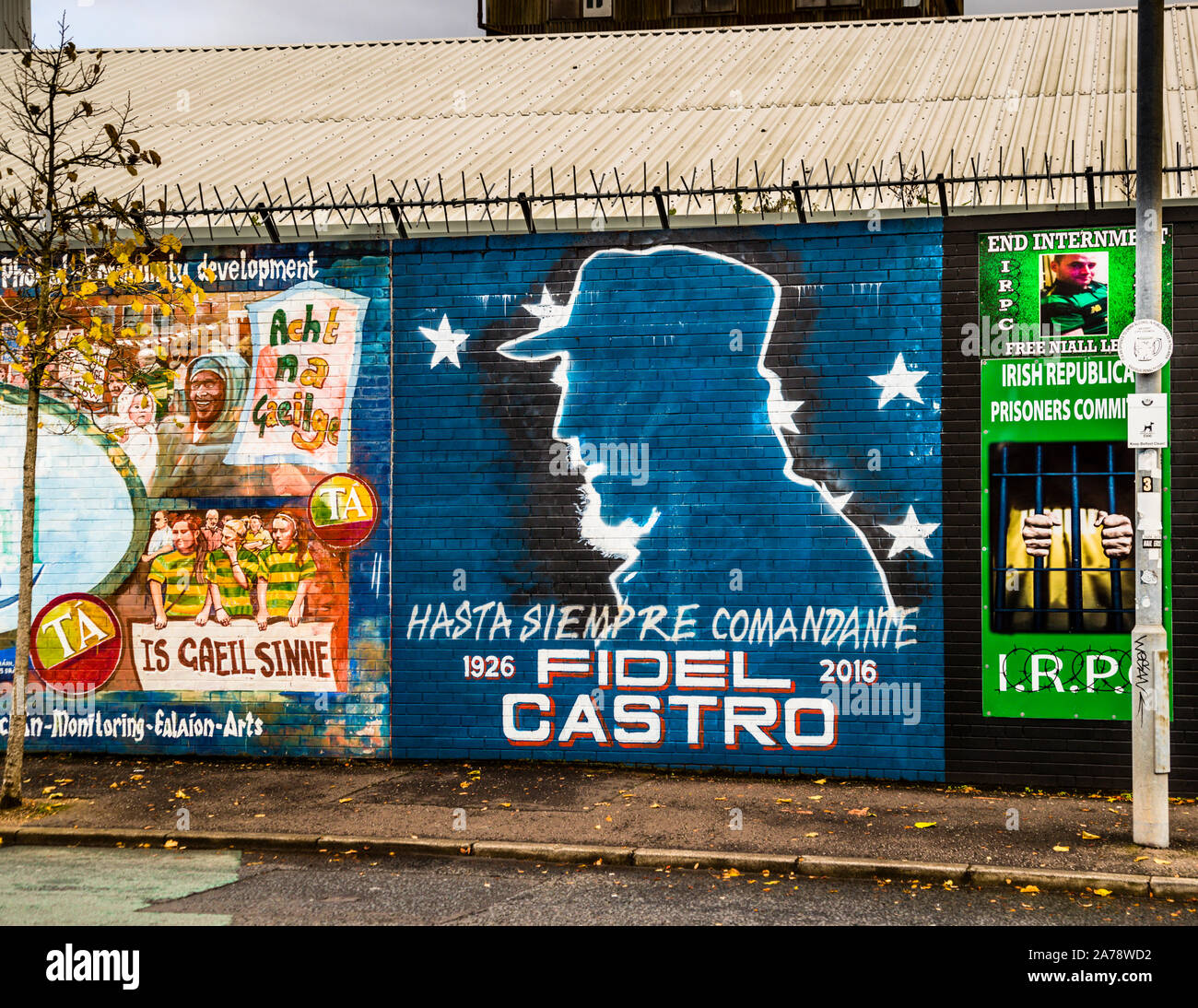 Ein Wandgemälde an der International Wall, Northumberland Street, Belfast, Nordirland, ehrt den kubanischen Revolutionsführer Fidel Castro (1926–2016) mit seiner Silhouette und dem Slogan „Hasta Siempre Comandante“; links davon ein Wandgemälde mit dem Titel „Is Gaeil Sinne“ („Wir sind irische Sprecher“), das Fotos von Kindern in grüner und gelber Kleidung zeigt und für die irische Sprache und den Irish Language Act („Acht na Gaeilge“) wirbt. Stockfoto