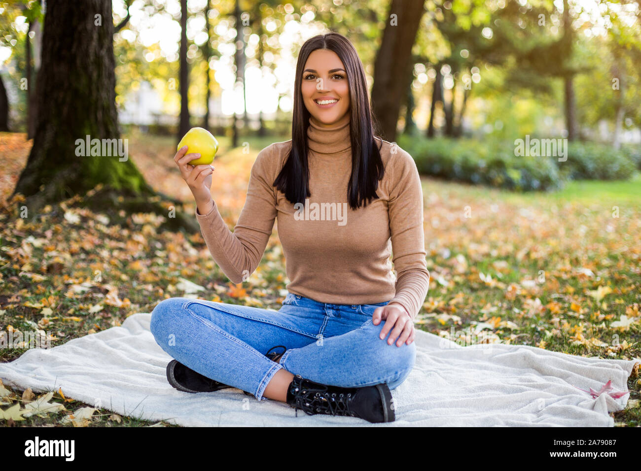 Schöne Frau essen Apple, während im Herbst genießt und Ruhen im Park Stockfoto