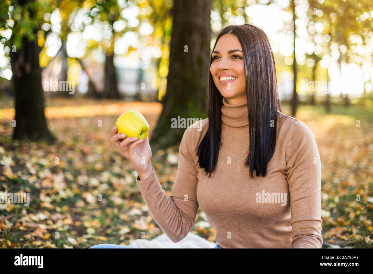 Schöne Frau essen Apple, während im Herbst genießt und Ruhen im Park Stockfoto