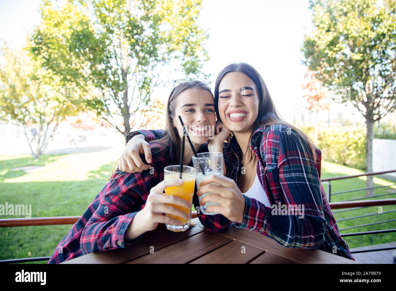 Zwei junge Frauen trinken Saft und Limonade in den Park an einem sonnigen Tag Stockfoto